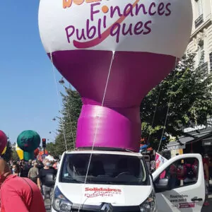 Solidarités finances publiques montgolfière arche gonflable manifestation paris posée sur le toit d'un camion.