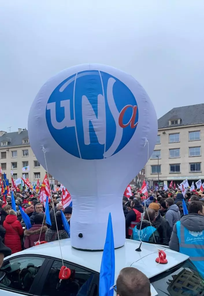 montgolfière gonflable blanche et bleu UNSA accroché à une voiture pendant la manifestation